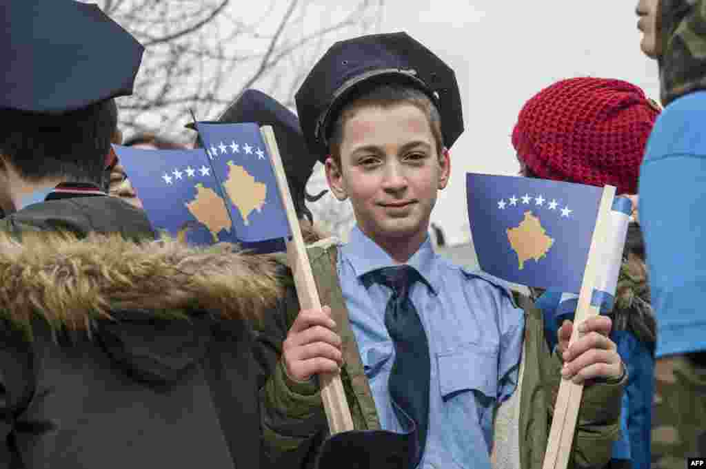 A young Kosovar boy dressed as police officer holds Kosovo flags in Pristina, on the eve of the celebrations of the 10th anniversary of Kosovo independence.