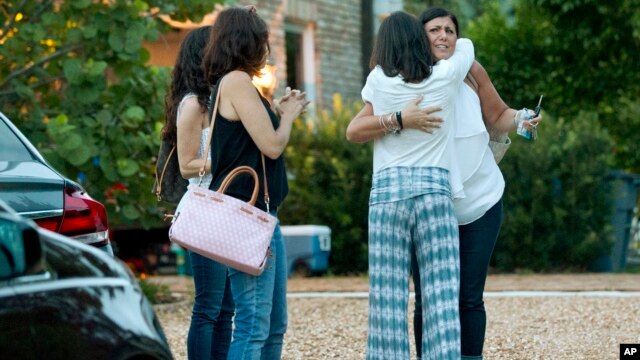 Vecinos consuelas a la madre de uno de los adolescentes desaparecidos cuando salieron a pescar en Tequesta, Florida.