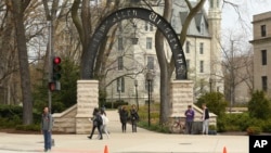 In this Friday, April 29, 2016, photo, people stand near the entrance gate to Northwestern University in Evanston, Ill. (Chris Walker/Chicago Tribune via AP)