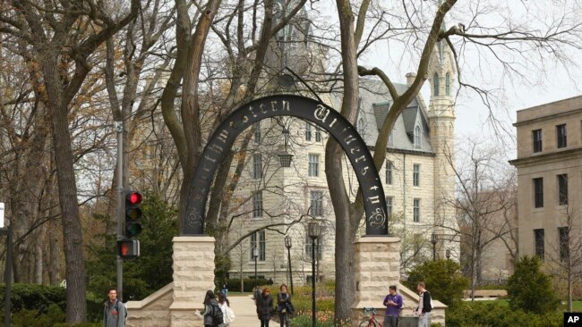 In this Friday, April 29, 2016, photo, people stand near the entrance gate to Northwestern University in Evanston, Ill. (Chris Walker/Chicago Tribune via AP)