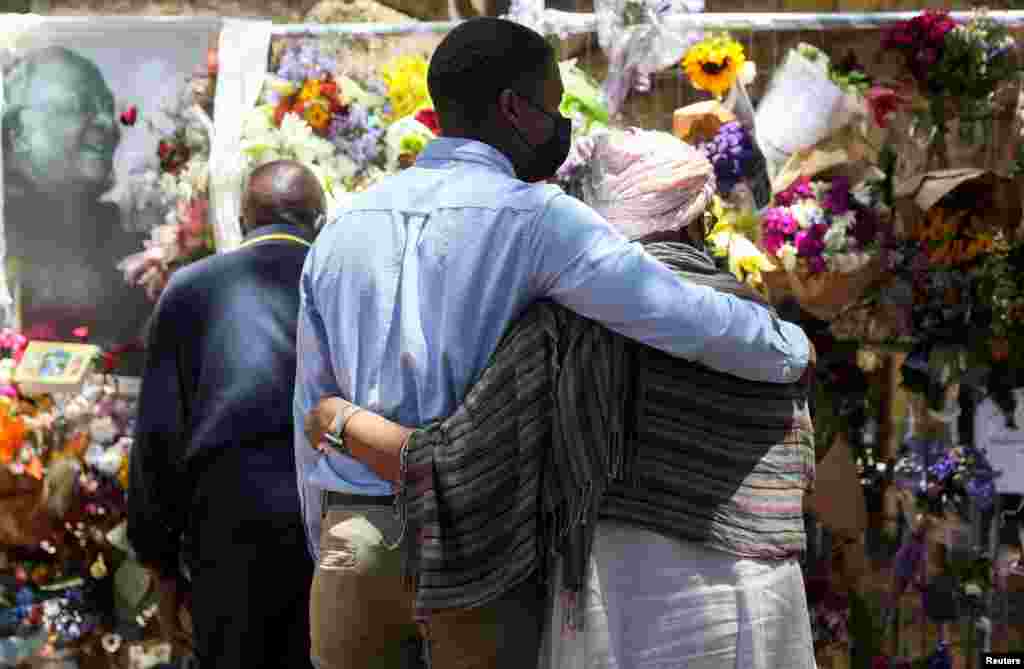 Family members of late Archbishop Desmond Tutu embrace at the remembrance wall after reading messages from the public, outside the St. Georges Cathedral, in Cape Town, South Africa.