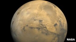 File - The largest canyon in the Solar System cuts a wide swath across the face of Mars. Named Valles Marineris, the grand valley extends more than 3,000 kilometers long, spans as much as 600 kilometers across, and delves as much as 8 kilometers deep. Photo Cred