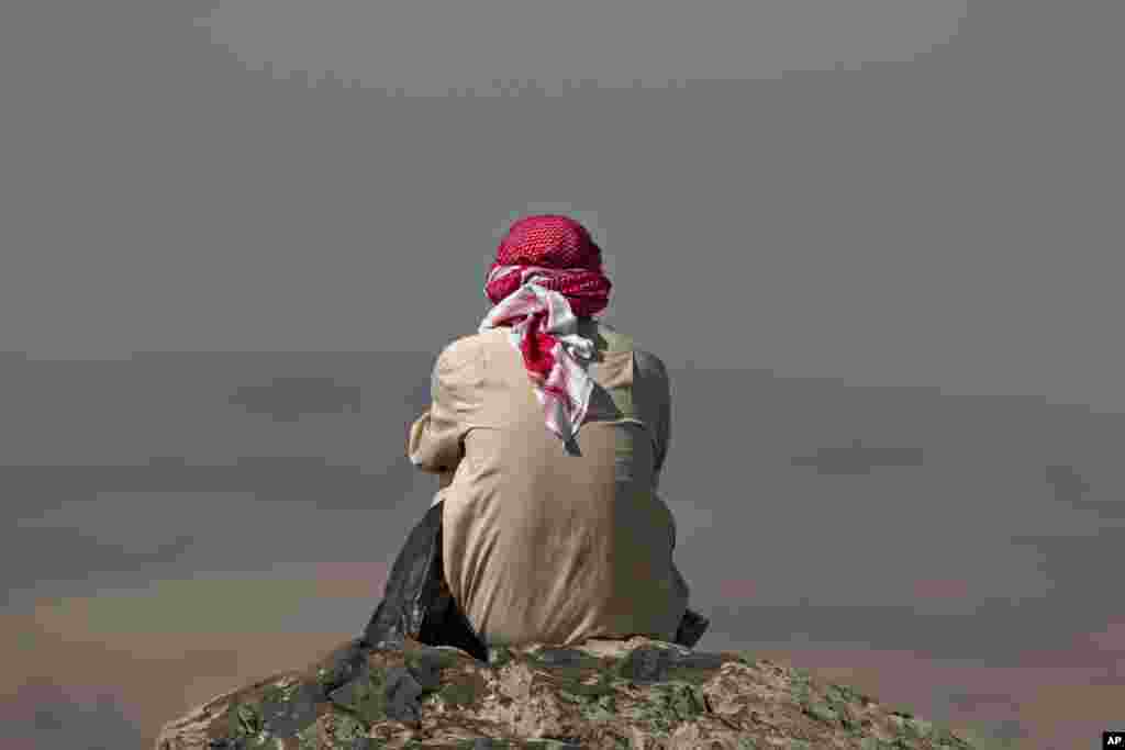 Một người ngồi nhìn chiến sự bên kia biên giới ở Kobani trên đỉnh đồi ở ngoại ô thị trấn Suruc, gần biên giới Thổ Nhĩ Kỳ-Syria. 