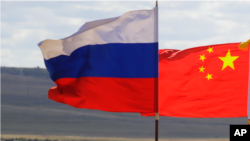 Bendera China dan Rusia sedang berkibar. China telah menyangkal laporan yang menyatakan para pejabatnya memberitahu mitra-mitra Rusia mereka untuk menunda invasi ke Ukraina hingga setelah Olimpiade Musim Dingin Beijing. (Foto: AP)