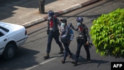 FILE - Police arrest a journalist in Yangon on February 27, 2021, as protesters were taking part in a demonstration against the military coup.