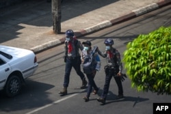 FILE - Police arrest a journalist in Yangon on February 27, 2021, as protesters were taking part in a demonstration against the military coup.