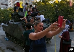 A woman takes a selfie in front a damaged Turkish military armored personnel carrier that was attacked by protesters near the Turkish military headquarters in Ankara, July 16, 2016.