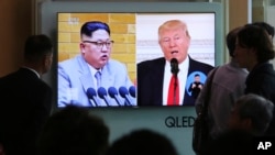 2018年4月21日，人们在韩国首尔火车站观看电视新闻，屏幕上显示美国总统川普和朝鲜领导人金正恩。