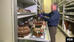 El curador Antonio Curet observa con detalle algunas de las más de 100 mil piezas indígenas en el Centro de Recursos del Museo Nacional del Indígena en Washington. 
