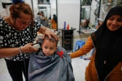 Francisca (kiri), seorang anggota komunitas transpuan, sedang memotong rambut anak kecil di salon tempat dia bekerja di Banda Aceh, 10 Desember 2012. (Foto: Reuters)