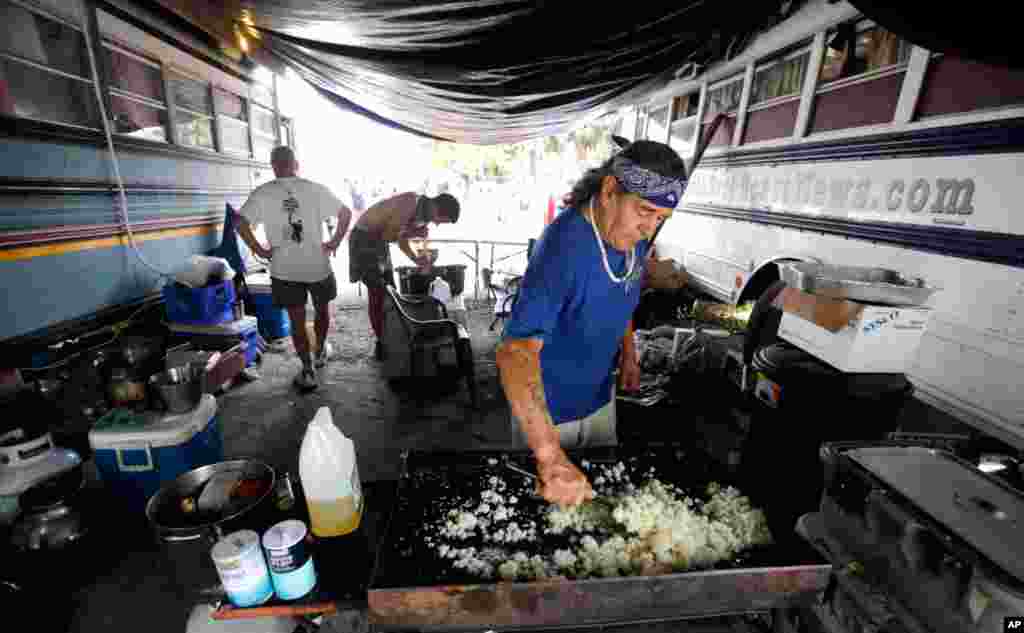 Homens preparam comida num acampamento de protesto chamado de vilarejo de Romney. 