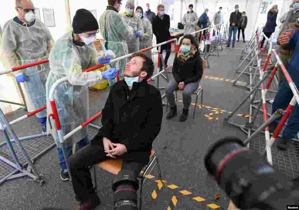 A medical employee explains how to collect a sample at a special coronavirus testing center for public service employees, as the spread of the coronavirus disease (COVID-19) continues, in Munich, Germany.