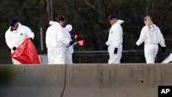 Officials investigate the scene where a suspect in a series of bombing attacks in Austin blew himself up as authorities closed in, March 21, 2018, in Round Rock, Texas. 