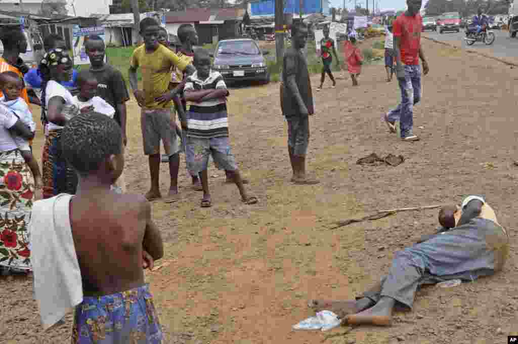 People stand around a man suspected of suffering from the Ebola virus in a main street in Monrovia, Liberia, Sept. 12, 2014.