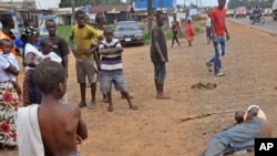 People stand around a man, right, suspected of suffering from the Ebola virus in a main street and busy part in Monrovia, Liberia, Friday, Sept. 12, 2014. 