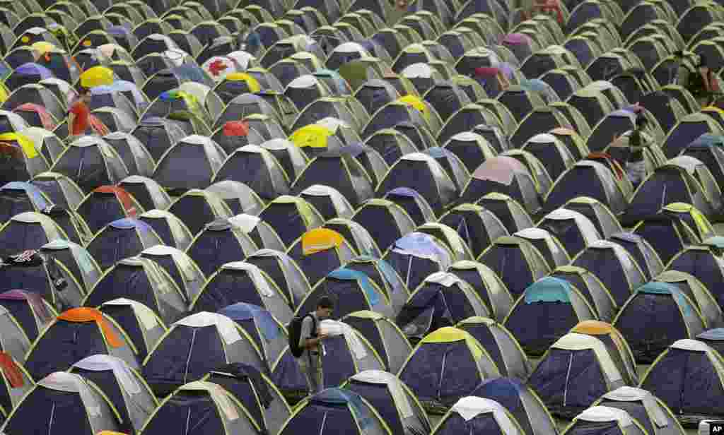 A participant walks between rows of tents lined up in the camping area during the Campus Party in Sao Paulo, Brazil.