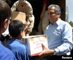FILE - Zalmai Khalilzad, U.S.'s special envoy and ambassador to Afghanistan (R) hands out parcels of toys sent by U.S. people to an orphanage in Kabul, providing meals and schooling for street children, August 8, 2004.
