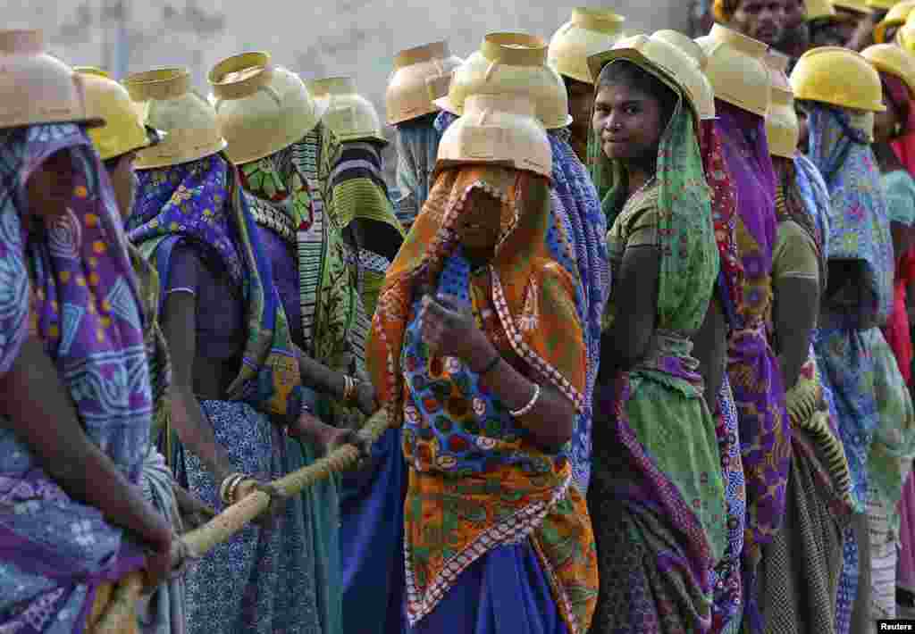 Female laborers wearing helmets take a break from laying underground electricity cables in Ahmedabad, India.