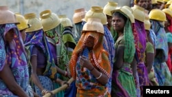 Female labourers wearing helmets take a break from laying underground electricity cables in Ahmedabad, India, March 7, 2016. 
