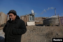 FILE - Setevdorj Myagmartsogt smokes a cigarette outside his tent-like ger home, which is heated by coal burning stove, in Ulaanbaatar, Mongolia, Jan. 29, 2017.