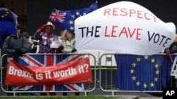 Brexit supporters and opponents with signs and flags are seen outside the Houses of Parliament in London, Britain, March 12, 2019.