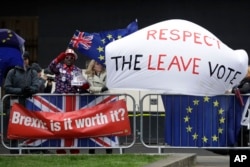 Signs of Brexit supporters and opponents are seen outside the Houses of Parliament in London, Britain, March 12, 2019.