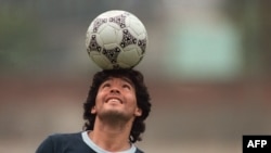 FILE: Argentine soccer star Diego Maradona, wearing a diamond earring, balances a soccer ball on his head as he walks off the practice field following the national selection's 22 May 1986 practice session in Mexico City.