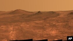 FILE - This composite of March 2015 photos made available by NASA shows a shallow crater called Spirit of St. Louis, about 110 feet (34 meters) long and about 80 feet (24 meters) wide, with a floor slightly darker than surrounding terrain.