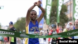 Ebisa Ejigu crosses the finish line of the Quebec City Marathon in Canada. Ejigu borrowed the crossed arm protest from Ethiopian marathon runner Feyisa Lelisa.