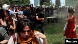 A Turkish riot policeman uses tear gas as people protest against the destruction of trees in a park brought about by a pedestrian project, in Taksim Square in central Istanbul, May 28, 2013. 