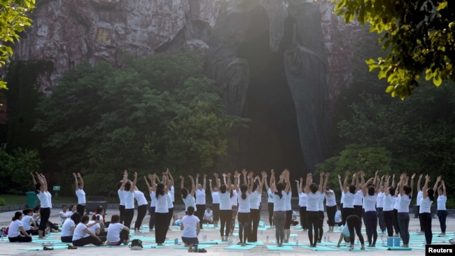 中国江苏淮安市钵池山公园的巨型老子雕像前，人们在国际瑜伽日练习瑜伽（2018年6月21日）