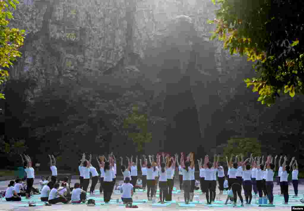 中国江苏淮安市钵池山公园的巨型老子雕像前，人们在国际瑜伽日练习瑜伽（2018年6月21日）。
