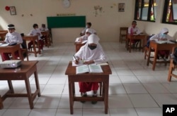 Siswa yang mengenakan masker duduk terpisah saat uji coba kelas sebuah sekolah dasar di Jakarta, Jumat, 4 Juni 2021. (Foto: AP)