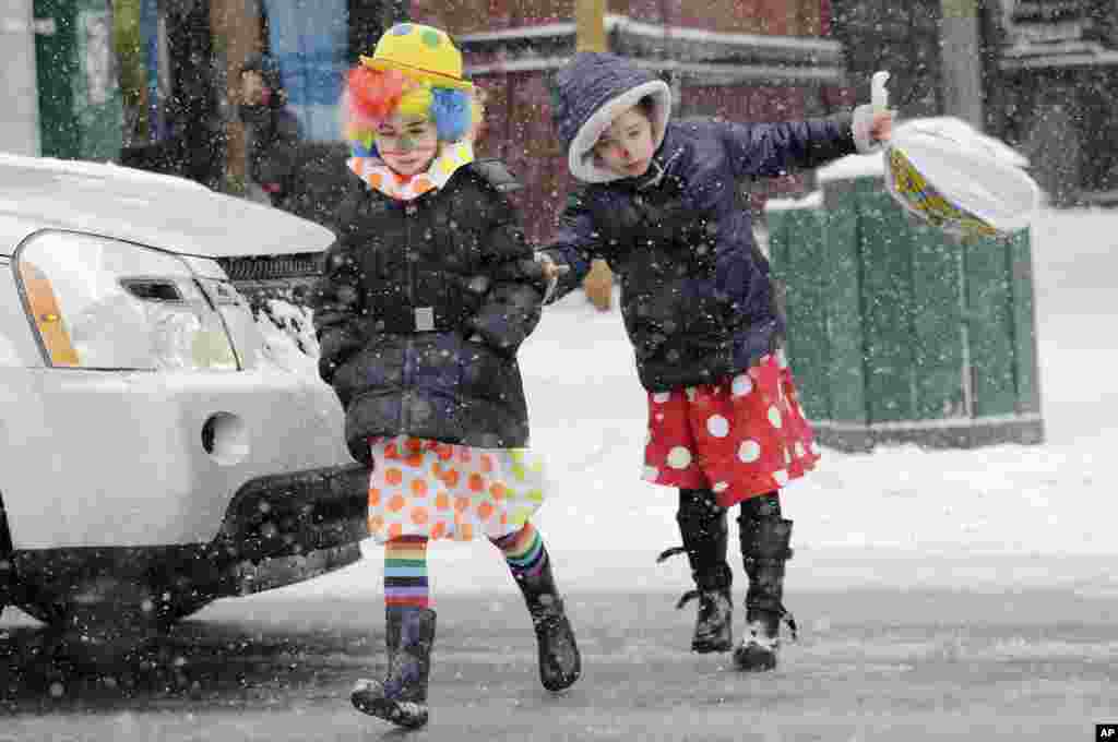 A girl slips on an icy street while walking with her sister in the Brooklyn borough of New York. The girls were dressed as clowns for the Jewish celebration of Purim.