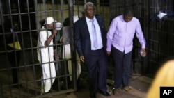 FILE: Zimbabwe's former finance minister, Ignatius Chombo, center and Kudzanai Chipanga are led to a prison truck in Harare, Zimbabwe, Nov. 25, 2017. Chombo testified that armed men in masks and uniforms abducted him from his home during the military operation