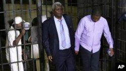  Zimbabwe's former finance minister, Ignatius Chombo, center and Kudzanai Chipanga are led to a prison truck in Harare, Zimbabwe, Nov. 25, 2017. Chombo testified that armed men in masks and uniforms abducted him from his home during the military operation