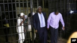 FILE - Zimbabwe's former finance minister, Ignatius Chombo, center and Kudzanai Chipanga are led to a prison truck in Harare, Zimbabwe, Nov. 25, 2017.