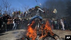 A masked supporter of imprisoned Kurdish rebel leader Abdullah Ocalan jumps over a Nowruz fire during the Nowruz celebrations in Istanbul, Turkey, March 22, 2015.