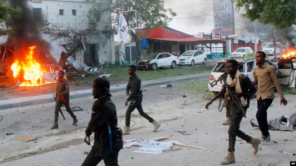 FILE - Security troops walk past burning cars after a fatal car bomb attack on a restaurant in Mogadishu, Somalia, May, 8, 2017. Al-Shabab militants claimed responsibility for the blast. Somalia's states on Sept. 8, 2018, suspended all ties with the central government, contending that it had taken its eye off the fight against al-Qaida-linked Islamist militants.