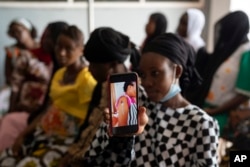 Oumie Nyassi shows a video circulating on the internet and that has been confirmed as fake news of a woman claiming she was magnetized after receiving the COVID-19 vaccine, in a doctors office at Serrekunda, Gambia hospital, Sept. 23, 2021.