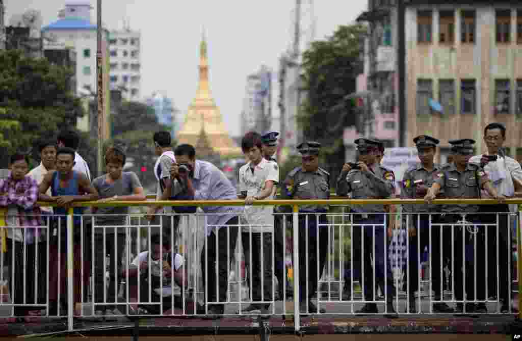 Burmese police officers and others take pictures of a group of pro-democracy students commemorating the 25th anniversary of the August 8, 1988 uprising, Rangoon, August 8, 2013.