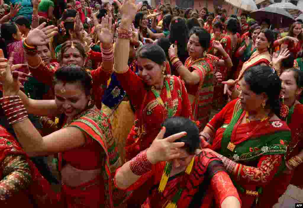 Nepalese Hindu women, dressed in red, dance after paying homage to Shiva, the Hindu god of destruction as they celebrate the Teej festival at the Pashupatinath temple area in Kathmandu.