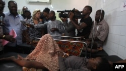 Ivory Coast President Alassane Ouattara (L) and his wife Dominique (C) stand next to a child, injured in a stampede, during a visit to the Cocody hospital in Abidjan, on January 1, 2013.