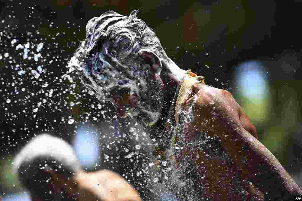 Porters wash themselves as police splash water with canon vehicles before taking them to a quarantine center in the capital Colombo, Sri Lanka.