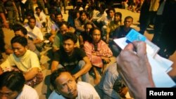 Buruh migran Indonesia menunggu petugas imigrasi Malaysia memeriksa status imigrasi mereka di luar Kuala Lumpur. (Foto: Reuters)