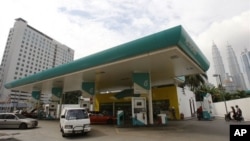 Motorists fill up their vehicles at Petronas petrol station in Kuala Lumpur, Malaysia, in this 2010 file photo. Many asian nations are seeing gains from lower oil prices. (AP Photo/Lai Seng Sin)