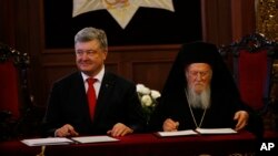 Ukraine's President Petro Poroshenko, left, and Ecumenical Patriarch Bartholomew I sign an agreement following their meeting at the patriarchate in Istanbul, Nov. 3, 2018.