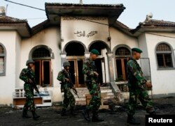 . Tentara berjalan melewati masjid pengikut Ahmadiyah yang dibakar massa di Desa Ciampea, Jawa Barat, 2 Oktober 2010.