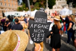 FILE - A woman holds a banner reading "Afghan sisters, you're not alone" during a demonstration in favor of Afghan women's rights, staged by women rights activists, in Rome, Sept. 25, 2021.