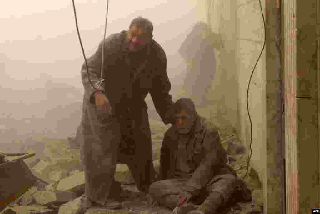 A Syrian man helps an injured man following an airstrike in Aleppo's Maadi neighborhood.